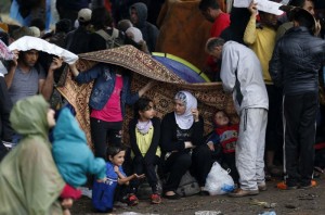 Migrants stand in front of barbed wire set by Macedonian police to stop thousands of migrants entering Macedonia illegally from Greece on the border line with Greece, near the train station of Idomeni, northern Greece, Saturday, Aug. 22, 2015. About 39,000 people migrants, have been registered as passing through Macedonia towards Europe in the past month, twice as many as the month before.    (AP Photo/Darko Vojinovic)