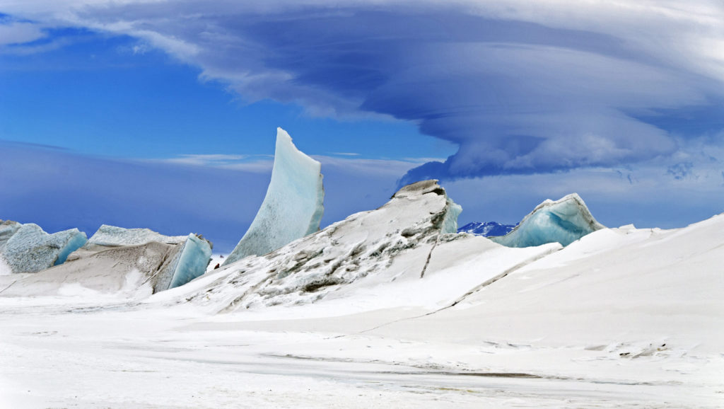 epa04203177 A handout picture made available by NASA on 13 May 2014 shows a multi-layered lenticular cloud hovering near Mount Discovery, a volcano about 70 km southwest of McMurdo Station on Ross Island, Antarctica, 24 November 2013. In 43 hours across five science flights in late November 2013, NASA's P-3 research aircraft collected more than 20,000 km worth of science data. Instruments gathered information about the thickness of the ice over sub glacial lakes, mountains, coasts, and frozen seas. The flights over Antarctica were part of Operation IceBridge, a multi-year mission to monitor conditions in Antarctica and the Arctic until a new ice-monitoring satellite, ICESat-2, launches in 2016. Lenticular clouds are a type of wave cloud. They usually form when a layer of air near the surface encounters a topographic barrier, gets pushed upward, and flows over it as a series of atmospheric gravity waves. Lenticular clouds form at the crest of the waves, where the air is coolest and water vapor is most likely to condense into cloud droplets. The bulging sea ice in the foreground is a pressure ridge, which formed when separate ice floes collided and piled up on each other. EPA/MICHAEL STUDINGER HANDOUT EDITORIAL USE ONLY