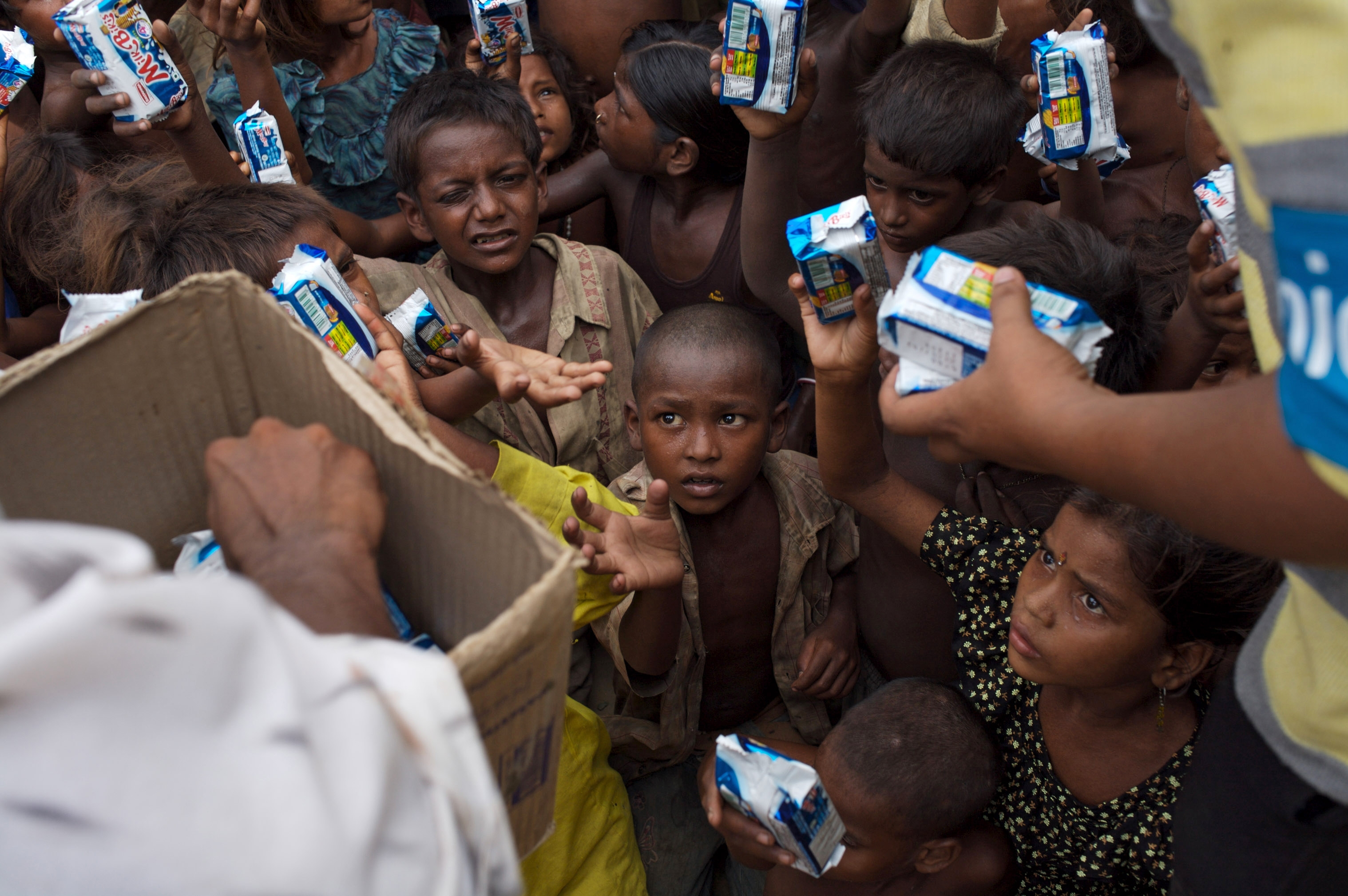 INDIA: Children gather for a distribution of supplies in the flood-affected village of Raban Toli, in Darbhanga District in the state of Bihar. The villagers are members of the very poor Musahar caste. The supplies have been brought to the village by the national NGO SCK (‘Samazik Chetna Kendra’, which means Social Awareness Centre) and include UNICEF-provided hygiene kits, fortified biscuits, ORS, water-purification tablets and tarpaulins for the community. Supplies must be hand-carried to communities where roads have been destroyed by the flooding. By late August 2007 in India, relief efforts continue in response to flooding caused by unusually intense monsoonal rains that began in June and that are also devastating parts of Bangladesh and Nepal. Many of the 38 million Indians affected by flooding live in Bihar, Uttar Pradesh and Bihar States in poor communities that already suffer from inadequate safe water and sanitation. More than 31,000 villages have experienced flooding and more than 1,800 people have died. Hospitals, roads and other vital infrastructure have been damaged or destroyed, hampering relief efforts. In Bihar State, 15 million people have been affected by flooding (including 1.5 million children under age five) and 2 million people are still living outdoors in emergency camps. To combat malnutrition, UNICEF is providing 250,000 iron and folic tablets for nursing and pregnant women and fortified biscuits for under-five children. UNICEF is also supporting temporary medical camps, relief sites and mobile medical units serving 25,000 patients a day. Pre-positioned emergency supplies – including plastic sheets for tents, sachets of oral rehydration salts (ORS), water purification tablets, temporary toilet sets, family hygiene kits, delivery kits and other relief materials – were distributed at the start of the emergency in seven affected districts.