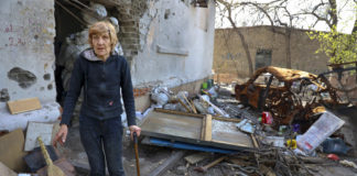 Γυναίκα δίπλα σε κατεστραμμένο σπίτι στην Ουκρανία