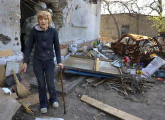Γυναίκα δίπλα σε κατεστραμμένο σπίτι στην Ουκρανία