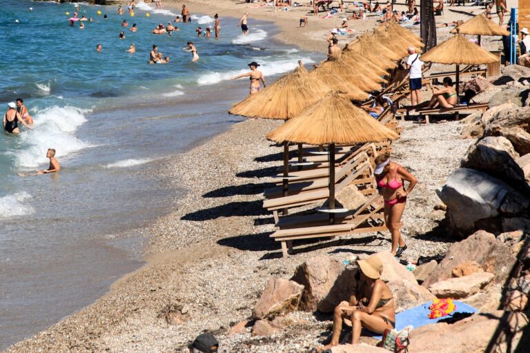 Κόσμος απολαμβάνει το μπάνιο του σε παραλία της Αττικής
